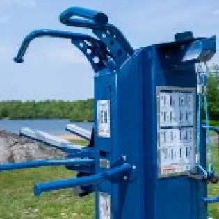 Outdoor fitness equipment in a community fitness park with instructional placards.